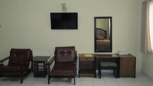 A room with a television mounted on the wall, a mirror, a sofa, a small table, and a cabinet. - Rumah Anda Guest House (Bandung)