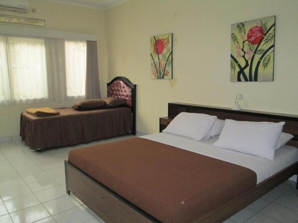 Una habitación de hotel con una cama grande, una cama más pequeña y un ventanal con cortinas.