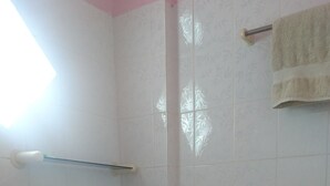 Un baño pequeño con azulejos, un inodoro, una ducha y un perchero para toallas.