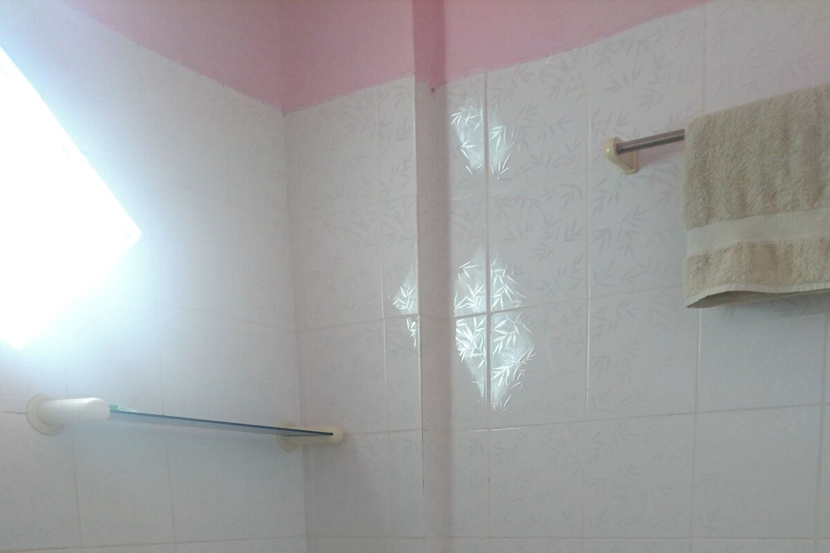 A small, tiled bathroom with a toilet, a shower area, and a towel rack.