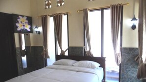 Una habitación de hotel con una cama grande, un espejo y cortinas en las ventanas.