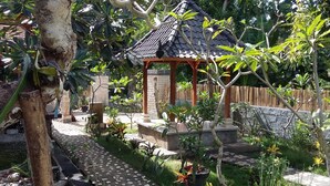 Un jardín con un pabellón, un sendero de piedra y diversas plantas.