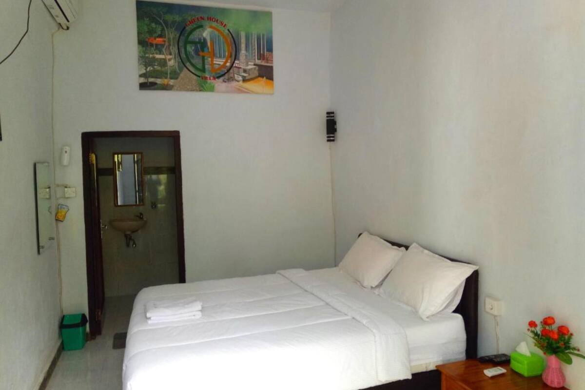 Une chambre d’hôtel avec un lit, une petite table sur laquelle est posé un vase de fleurs et un tableau accroché au mur.