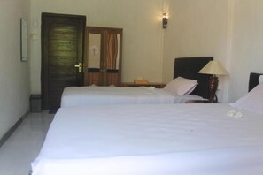 A hotel room with two single beds, a wooden wardrobe, a bedside table with a lamp, and a small trash bin. - Villa Green House (Penida Island)
