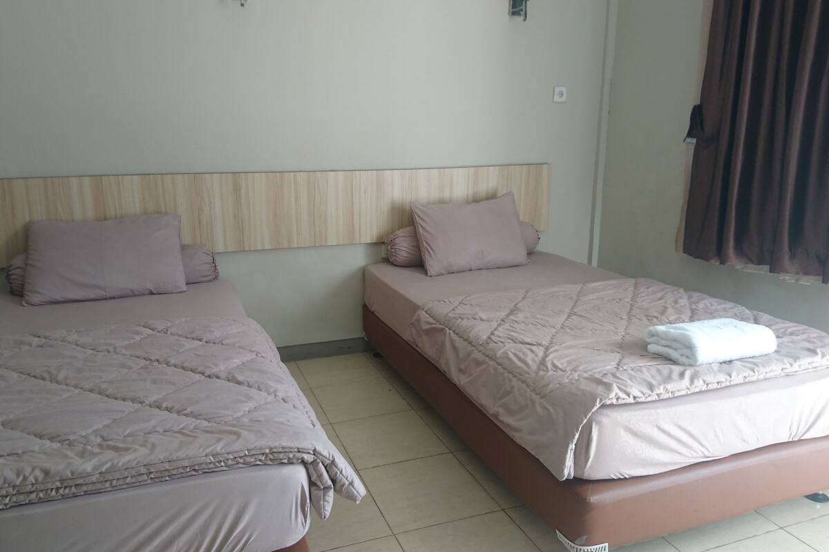 Two single beds with headboards, a brown mattress, and a white blanket on one bed.