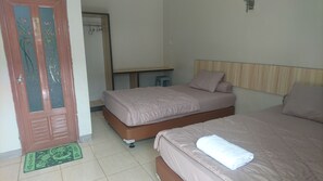 A hotel room with two beds, a desk, a chair, and a door with a decorative glass panel. - Liberty Homestay (Pekanbaru)