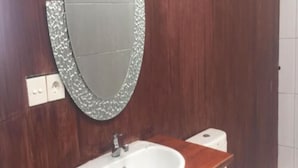 Een badkamer met een houten wastafelmeubel, een witte wasbak en een toilet.