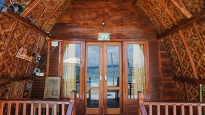 A wooden cabin with a balcony, a wooden door with a number sign, and a view of the sea. - Road Beach Villa (Penida Island)