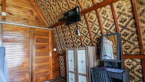 A room with wooden walls and a patterned ceiling, a television mounted on the wall, and a cabinet with a mirror. - Road Beach Villa (Penida Island)