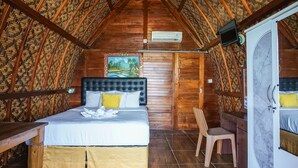 A cozy room with a bed, a chair, and a wardrobe. - Road Beach Villa (Penida Island)