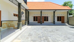 Un bâtiment doté d’un toit en tuiles, d’une entrée abritée et d’une cour pavée.