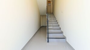 Un escalier avec une rampe, menant à un palier doté d’une fenêtre.