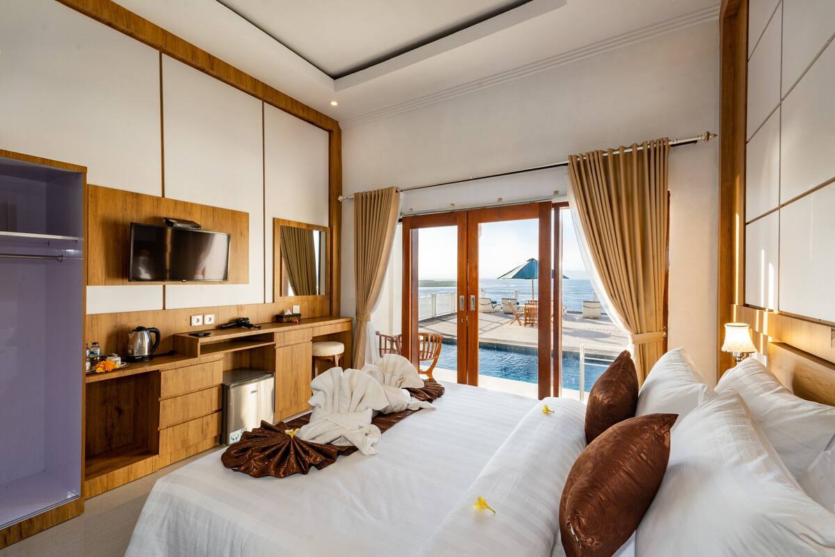 Una habitación de hotel con cama, escritorio, televisor y vista al mar.