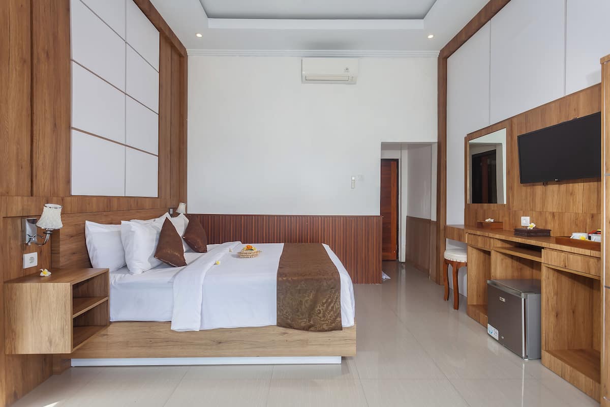 Una habitación de hotel moderna con una cama grande, paneles de madera, un televisor de pantalla plana y un refrigerador pequeño.
