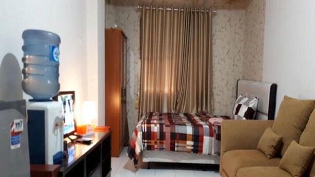 Una habitación de hotel pequeña con cama, sofá, escritorio con computadora y dispensador de agua.