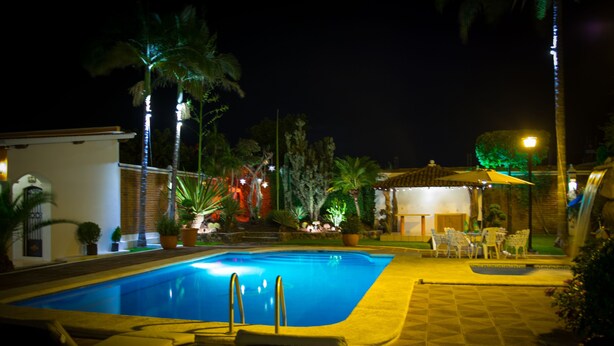 Piscina com espreguiçadeiras e um pequeno espaço coberto com assentos.