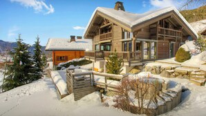 Een houten chalet met een balkon, omgeven door besneeuwde grond en bomen.