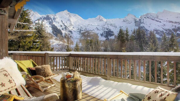 Een houten terras met uitzicht op besneeuwde bergen.
