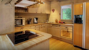 Een moderne keuken met houten kastjes, een ingebouwde magnetron, een koffiezetapparaat en een koelkast.
