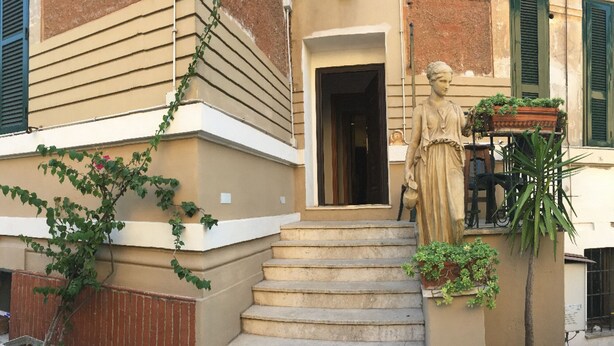 A building with a statue on the steps, a door, and some greenery. - Residence Villa Vittoria B&B (Rome)