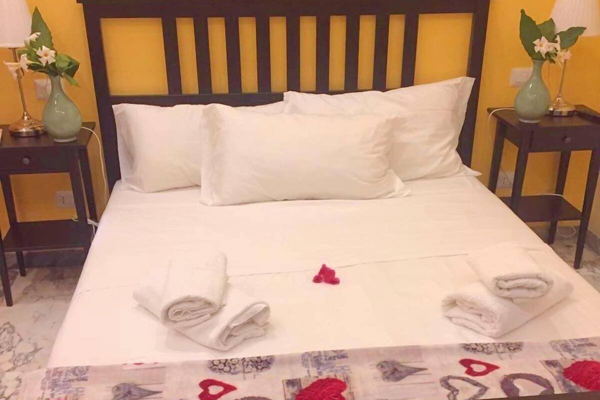 A bed with white linens, pillows, and a decorative towel arrangement.