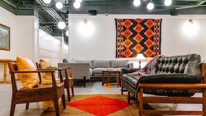 Una sala moderna con un sofá gris, sillas de madera y una alfombra roja.