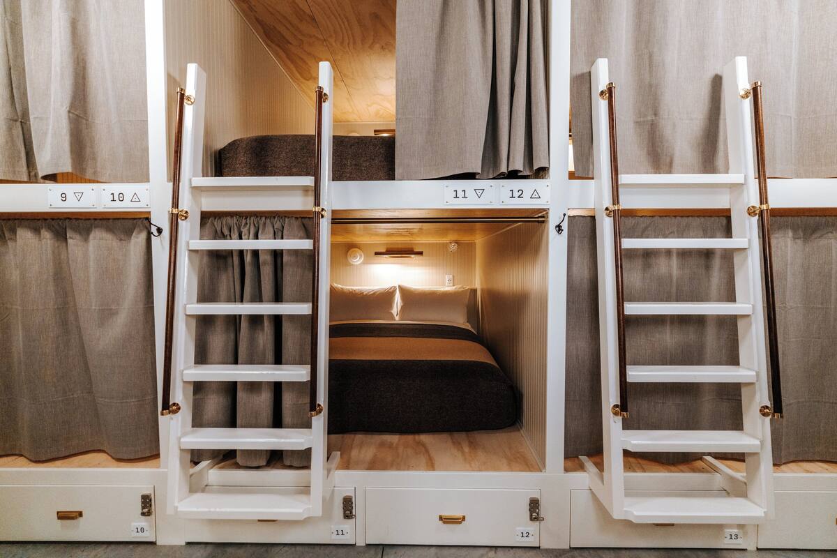 A bunk bed with a ladder, a small shelf, and a light fixture above the bed.