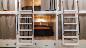 Una litera con escalera, un estante pequeño y una lámpara sobre la cama.