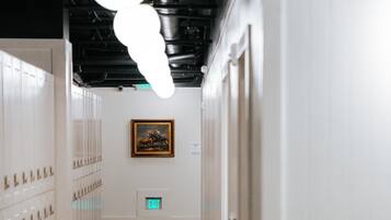 A hallway with lockers, a bench, and a framed picture on the wall.