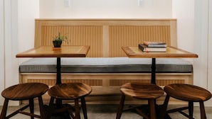 Un rincón pequeño y acogedor con un banco de madera y dos mesas, cada una con una sola silla.