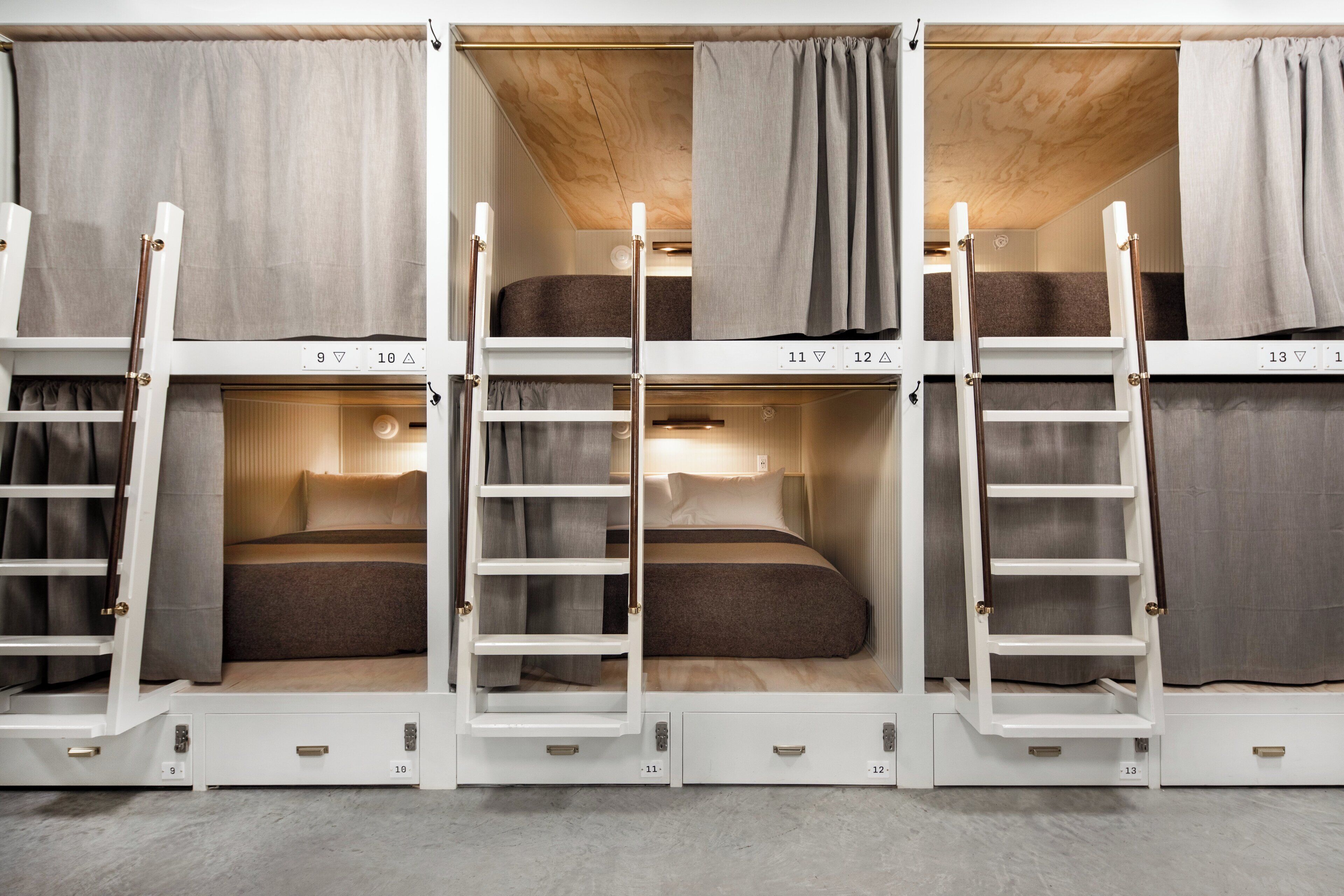 Une chambre avec des lits superposés à trois niveaux, chaque niveau étant équipé d’une échelle et d’un petit tiroir.