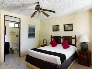 A bedroom with a bed, a ceiling fan, a nightstand with a lamp, and a bathroom visible through an open door. - Hotel Santa Rosa (General Cepeda)