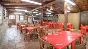 A rustic dining area with wooden tables and chairs, a tiled floor, and a wooden ceiling with exposed beams. - Hotel Santa Rosa (General Cepeda)