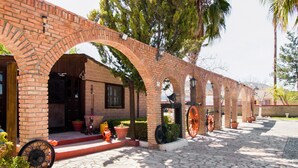 A brick building with arched walkways and a cobblestone pathway. - Hotel Santa Rosa (General Cepeda)