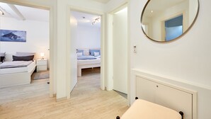 Une chambre moderne avec un grand lit, des tables de chevet, un miroir et une vue sur une autre pièce.