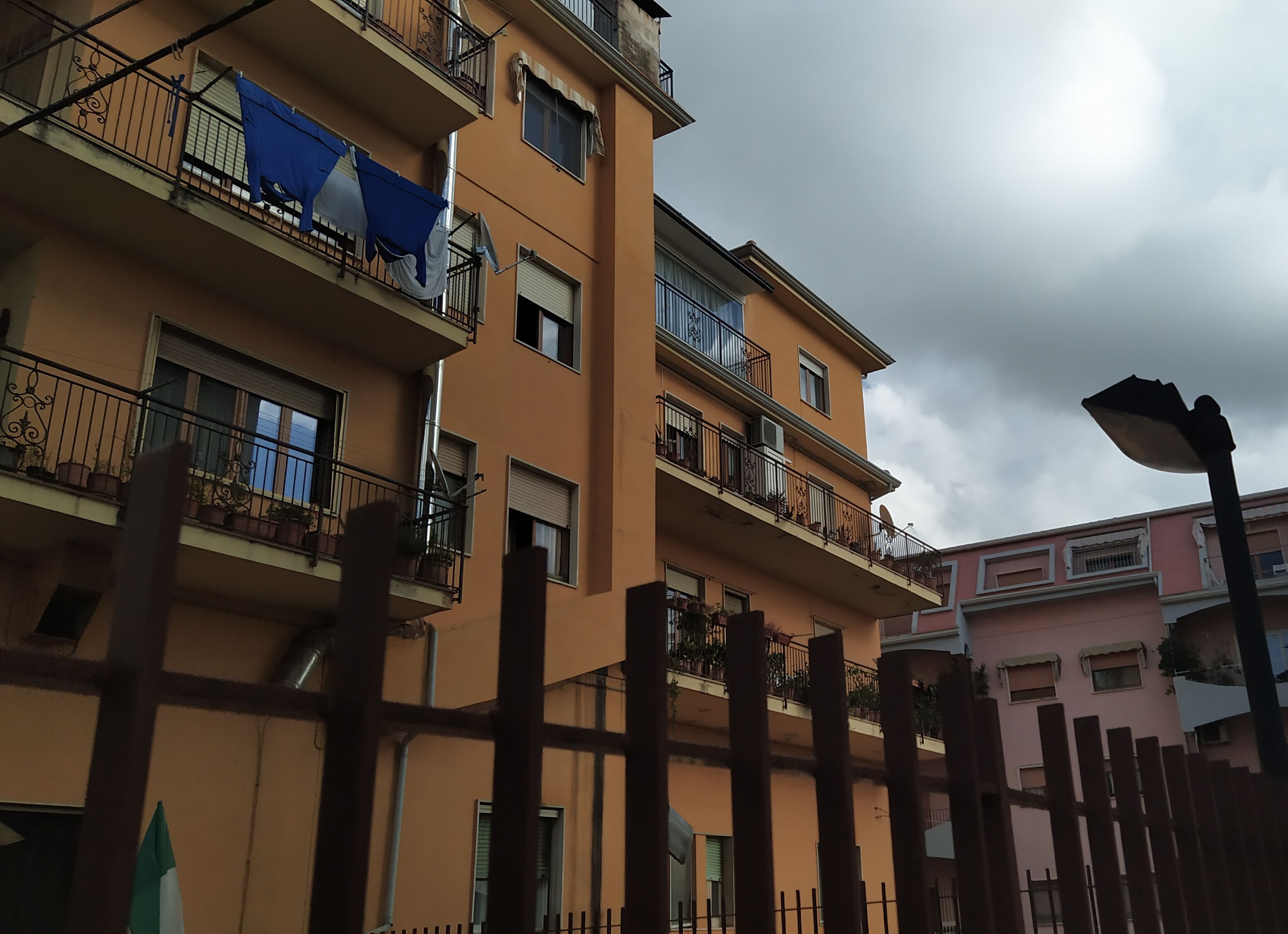 A multi-story building with balconies, some with potted plants.
