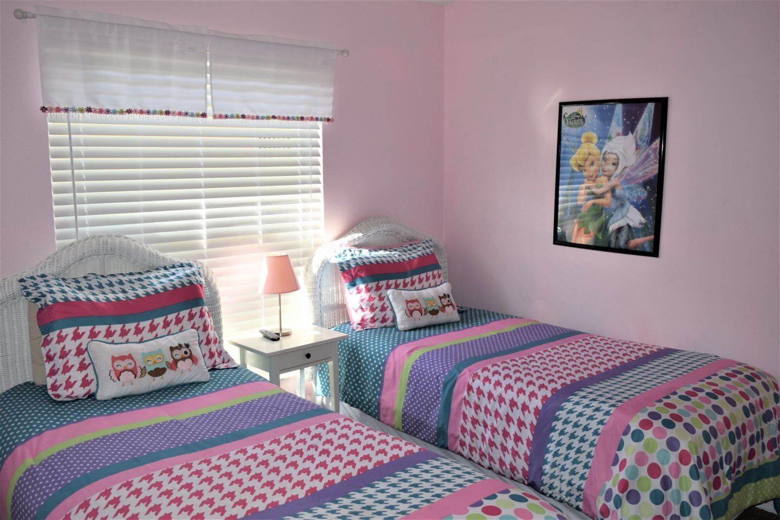 A bedroom with two beds, a nightstand, a lamp, and a framed picture on the wall.