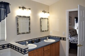 A bathroom with two sinks, wooden cabinets, and a patterned tile backsplash. - Indian_creek_8068 (Kissimmee)
