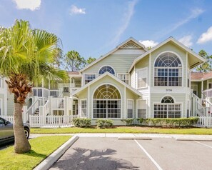 A large, two-story building with a symmetrical facade, large arched windows, and a white picket fence surrounding the property. - Royal_palm_bay_99 (Kissimmee)
