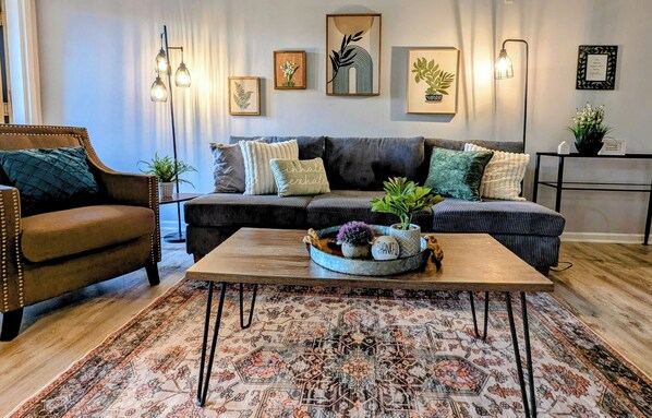 Ein gemütliches Wohnzimmer mit einem braunen Ledersofa, einem gemusterten Teppich und einem Couchtisch mit Dekoration.