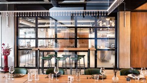 A modern dining area with a large window, wooden tables, and green chairs. - Campanile PRIME - Rungis Orly (Chevilly-Larue)