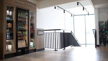A modern interior with a vending machine labeled 'MINI COMPTOIR' and a staircase leading to another level.