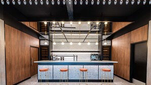 A modern kitchen with a central island, bar stools, and pendant lighting. - Campanile PRIME - Rungis Orly (Chevilly-Larue)