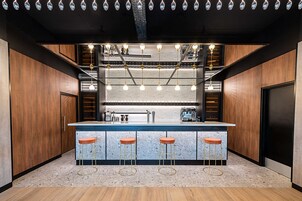 A modern kitchen with a central island, bar stools, and pendant lighting.
