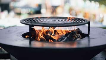 Una parrilla al aire libre redonda con llamas visibles.