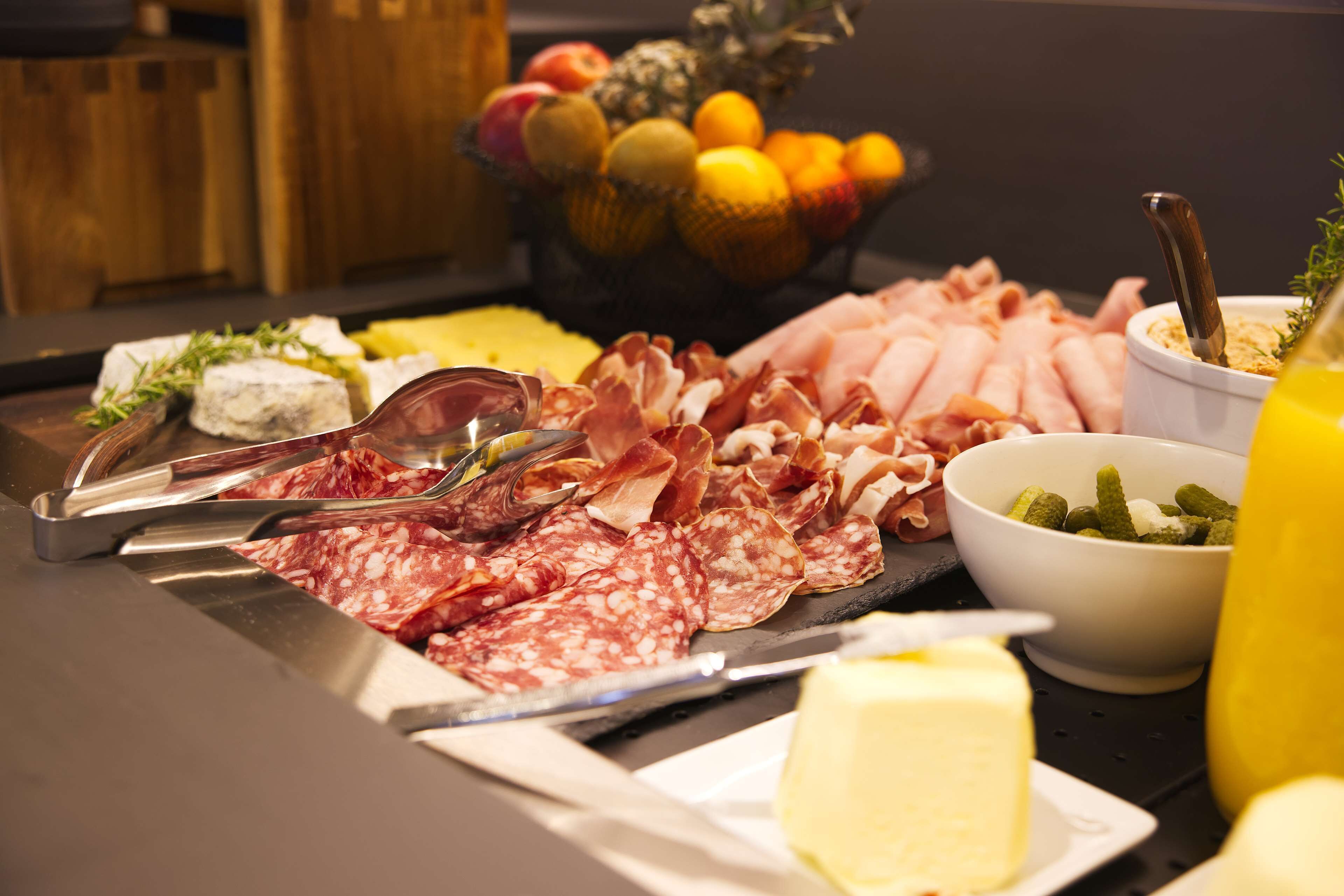 Un bufé con carnes, quesos y frutas variadas.