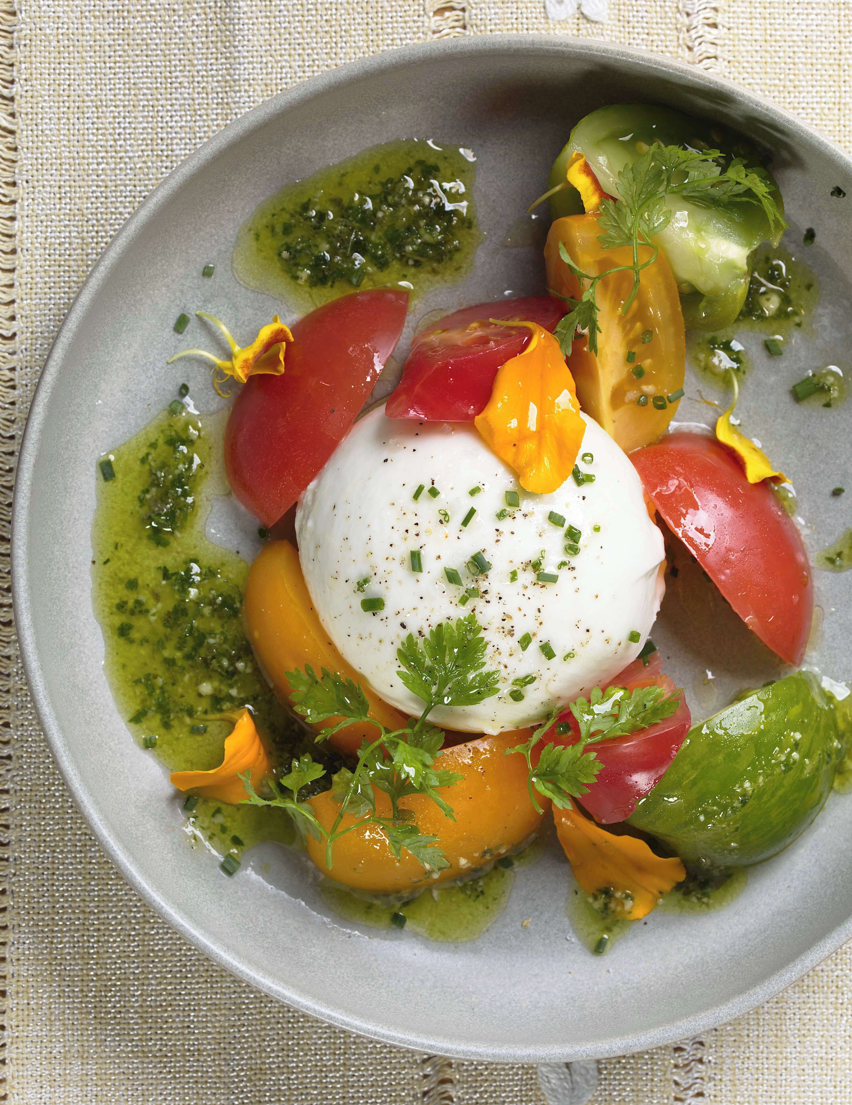 Un plat composé d’un œuf poché, de tomates et de légumes verts.
