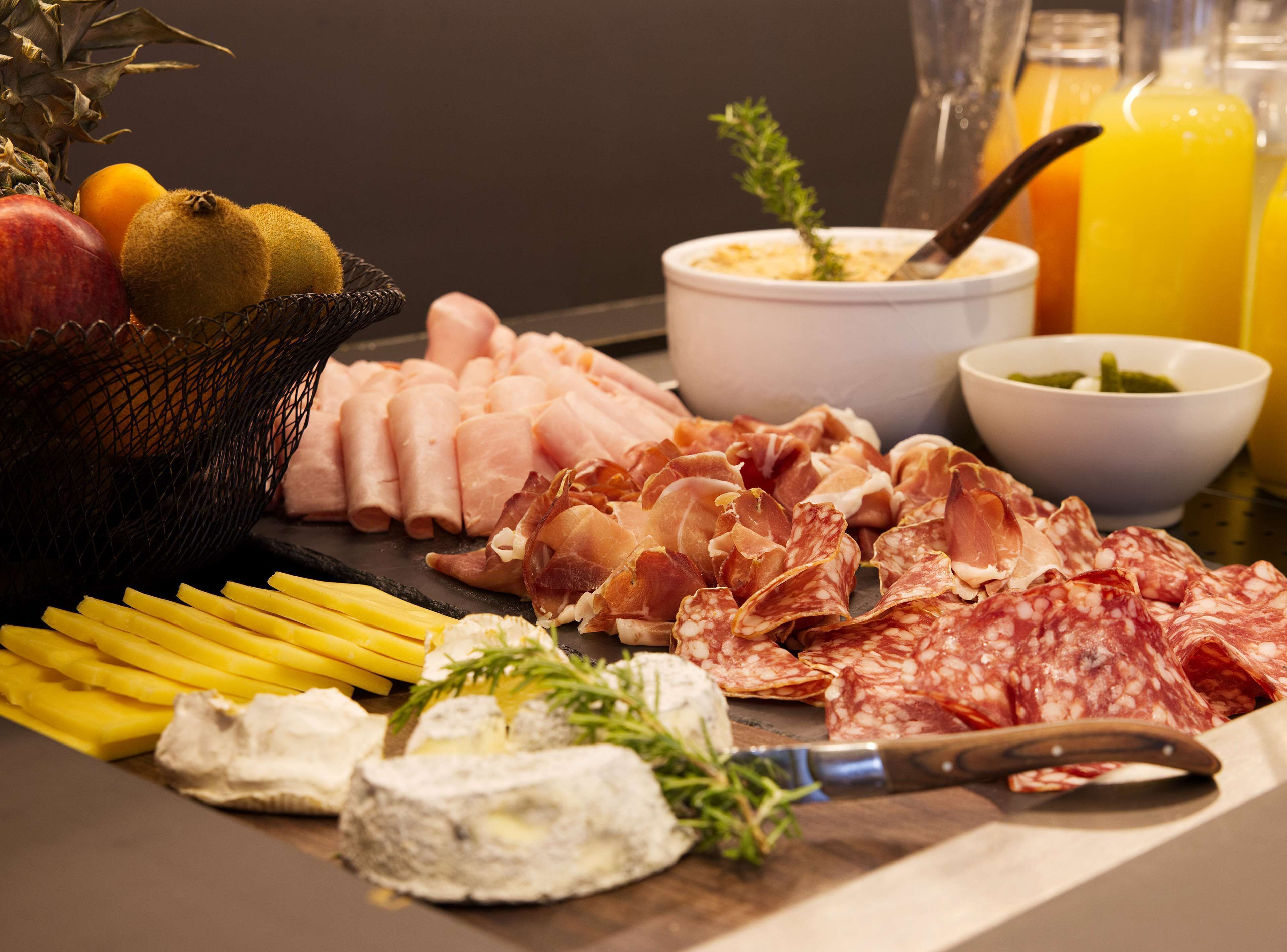 Una tabla de fiambres con diferentes carnes, quesos y frutas.