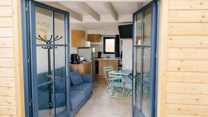 A wooden cabin with a living area, kitchenette, and dining space. - LE STUDIO, Gîte 3. Clos des Aigrettes,  30m from La Cotiniere Port (Saint-Pierre-d'Oléron)