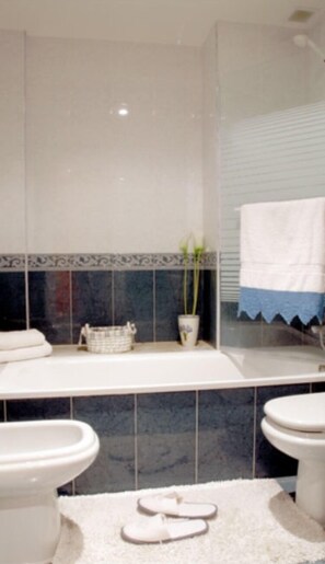 Bathroom features a white bathtub, sink, and tile walls.